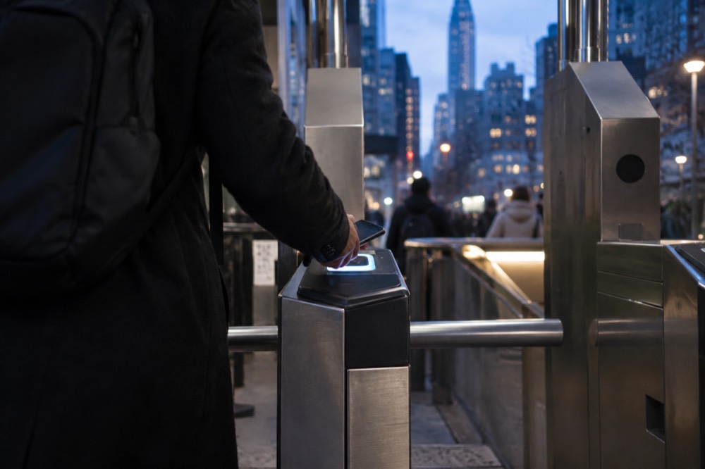 A rider tapping a phone at a subway turnstile