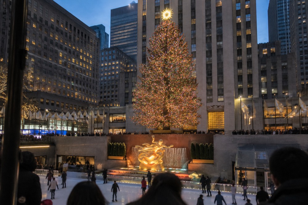 The Rockefeller Center Christmas tree glowing above the ice rink at dusk