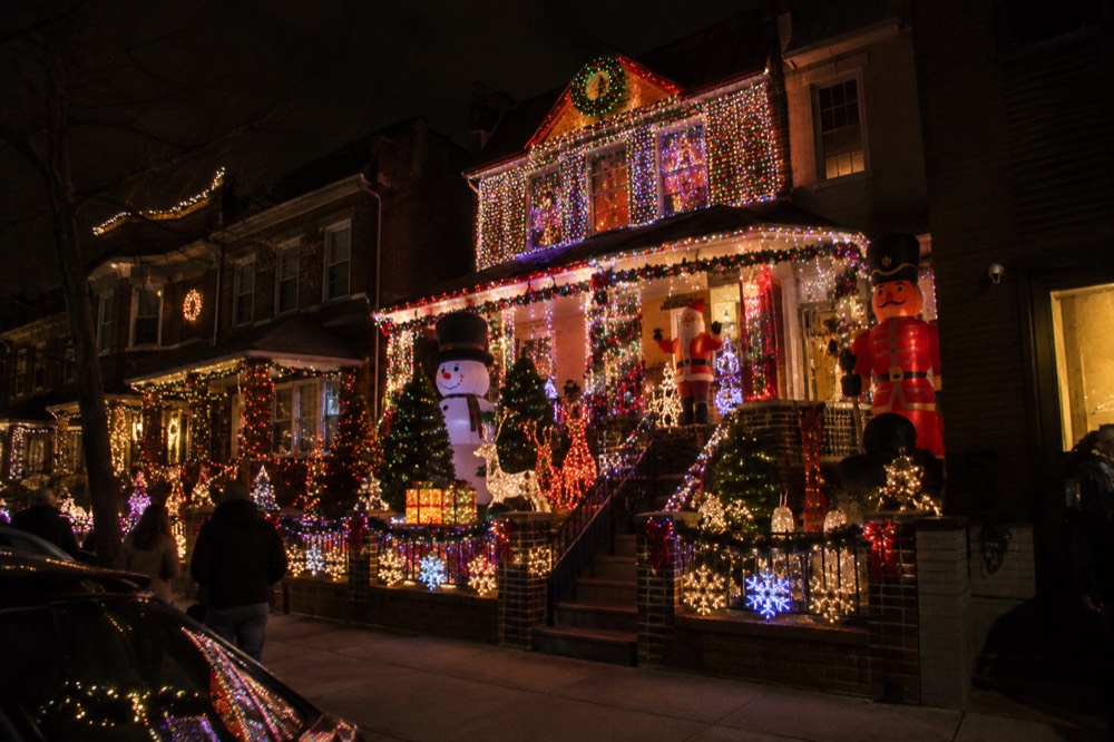 A Brooklyn house covered head to toe in colored Christmas lights and inflatables at night