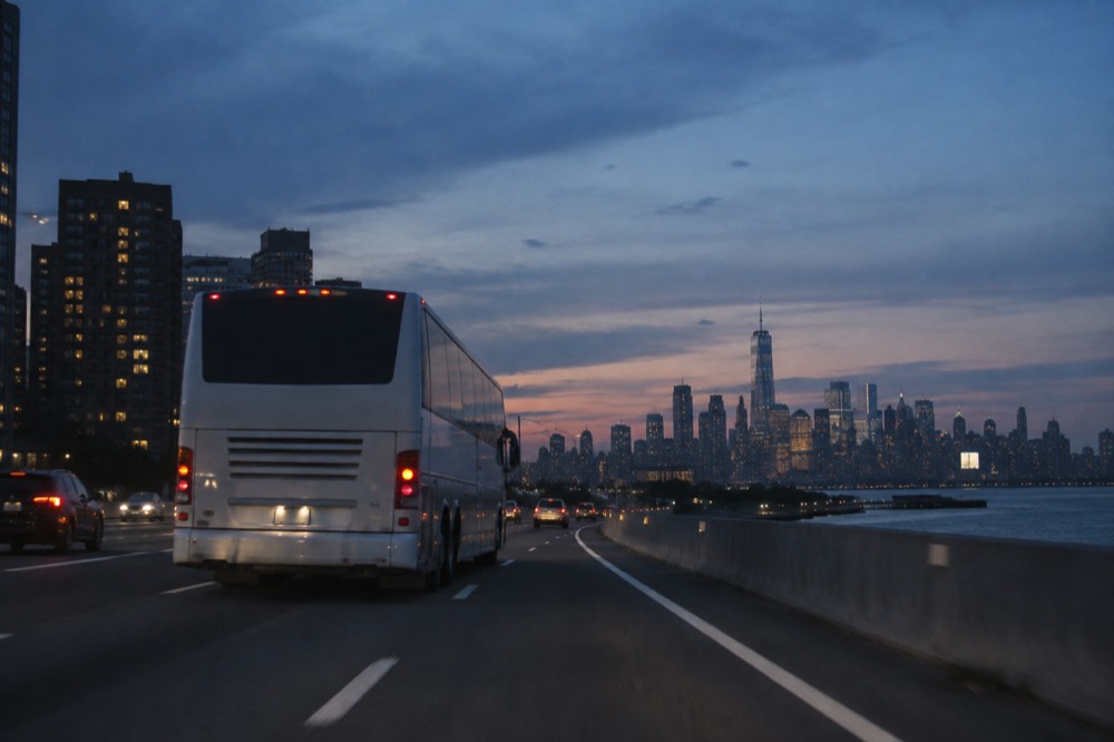 A coach bus on a highway with the Manhattan skyline receding in the background