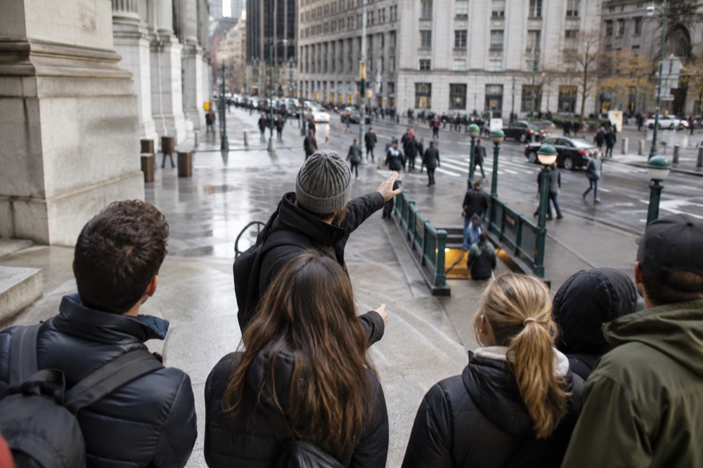 A guide speaking to a small group on a Lower Manhattan street
