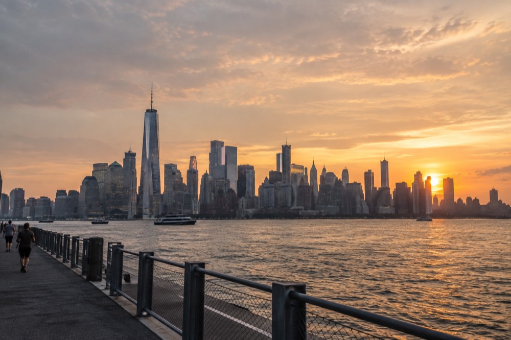 A wide view of the Manhattan skyline at sunset seen from across the water