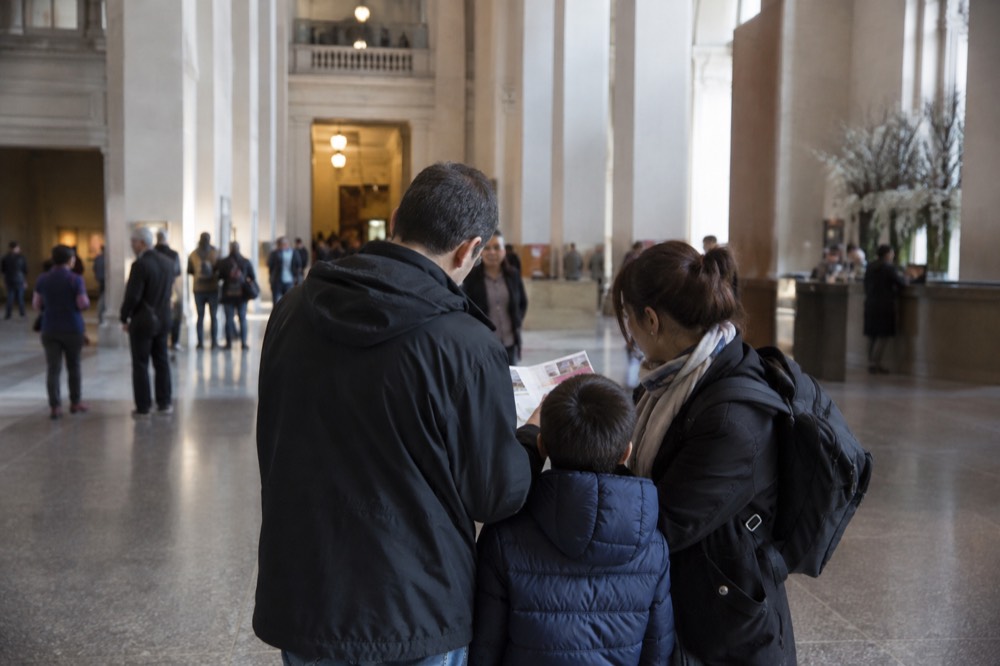 A family reading a city pass ticket while standing in a museum lobby
