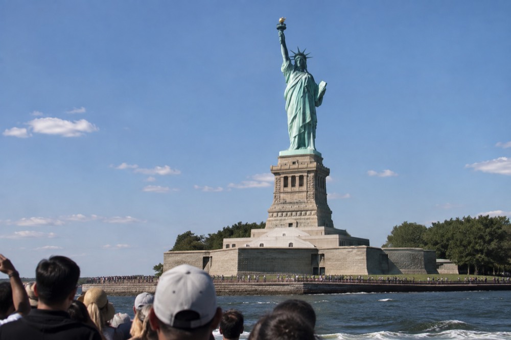 A sightseeing boat passing the Statue of Liberty in New York Harbor