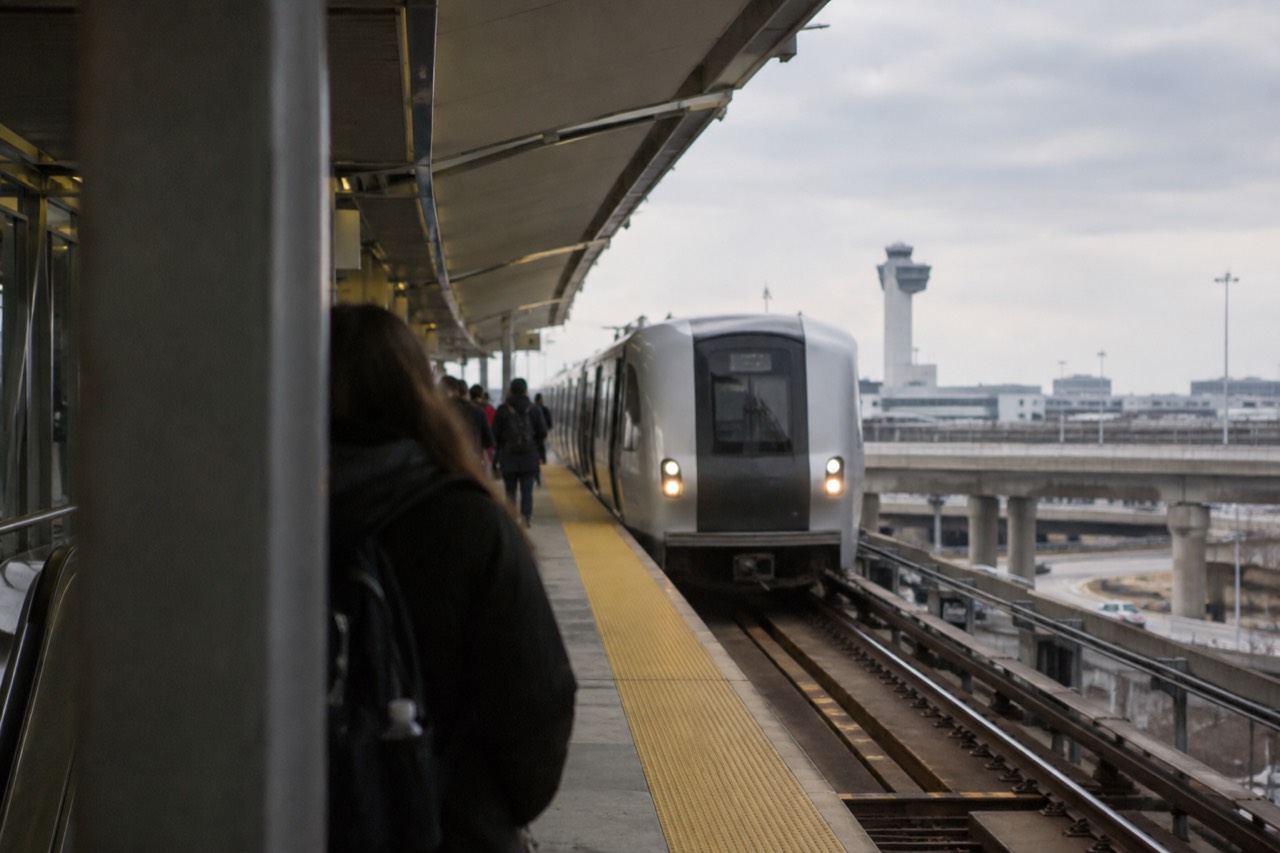 An AirTrain station platform at JFK Airport with a train arriving