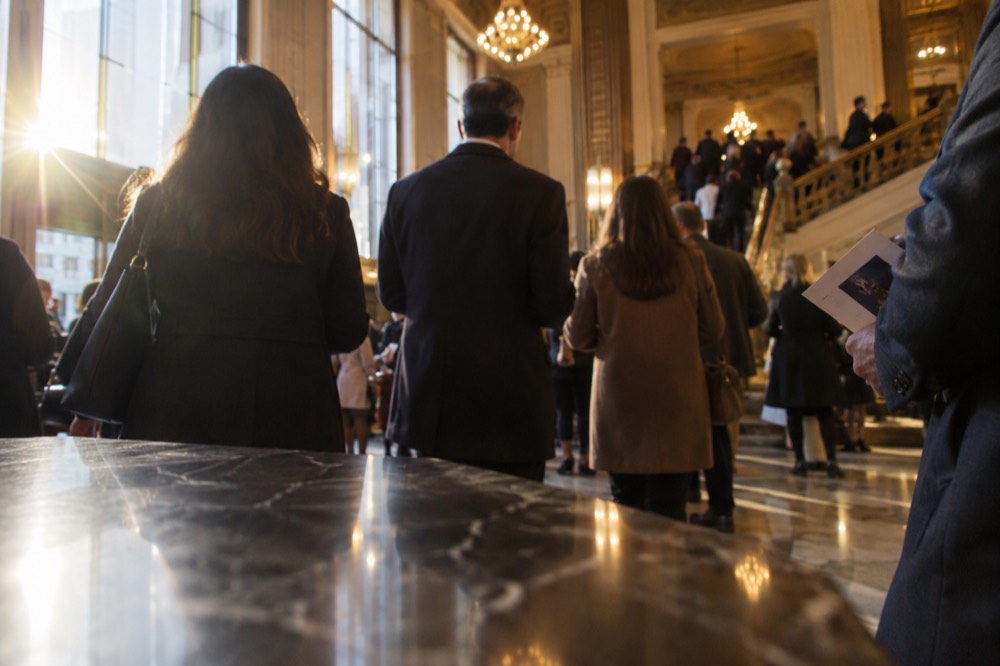 The lobby of a Broadway theater filling with attendees holding programs
