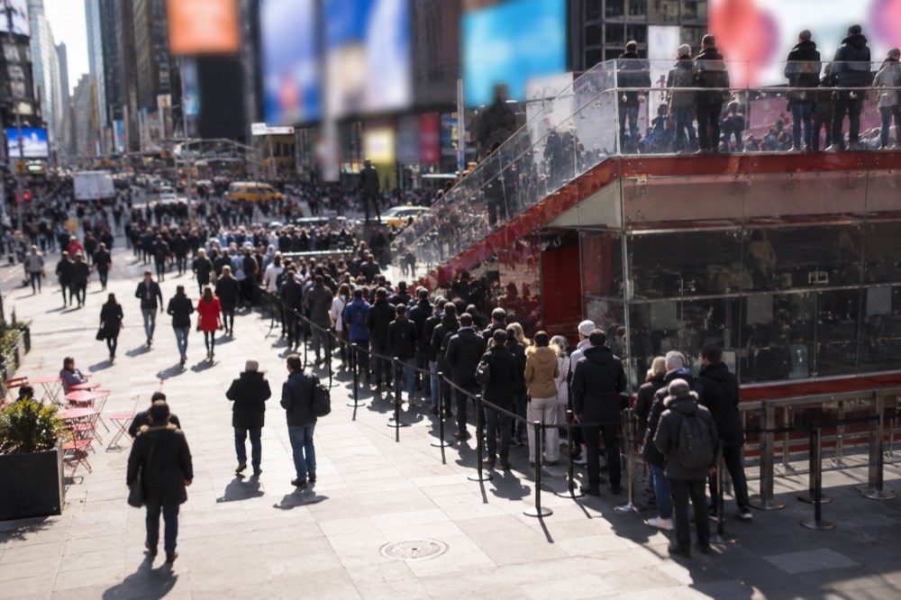 A TKTS discount ticket booth with a queue of people stretching across a Times Square plaza