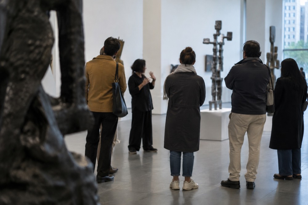 A guide speaking to a small group of visitors in a sculpture gallery