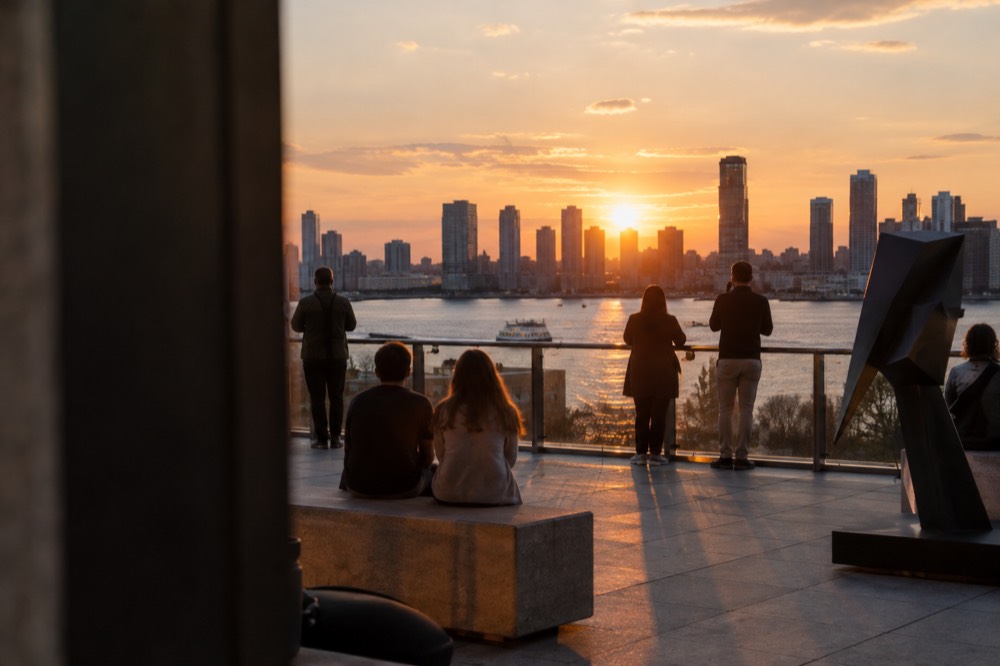 Visitors on a museum terrace overlooking the Hudson River at sunset