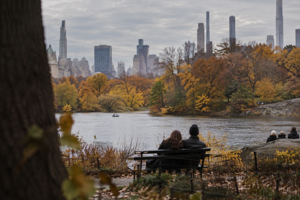Central Park in autumn with golden trees around the lake and the skyline beyond