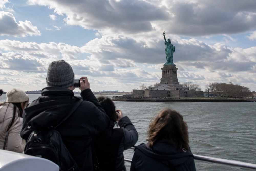 Tourists photographing the Statue of Liberty from a Circle Line sightseeing boat