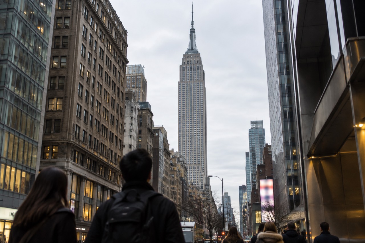 Visitors looking up at the Empire State Building from a Midtown street