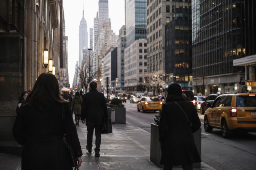 People in coats walking past a Manhattan street with yellow taxis