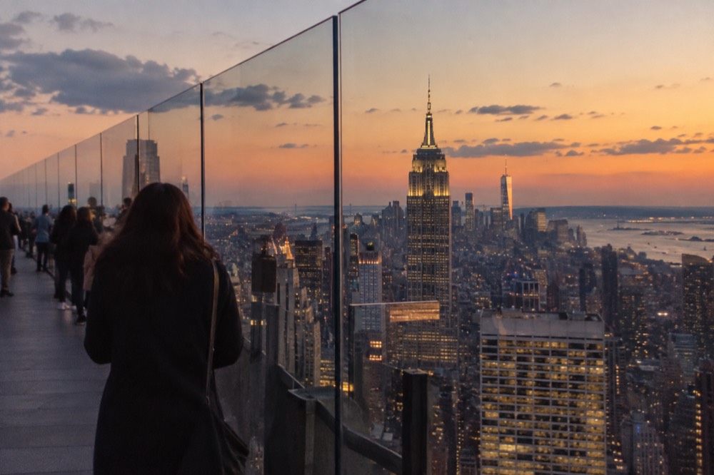 A Manhattan observation deck at dusk with the skyline lighting up