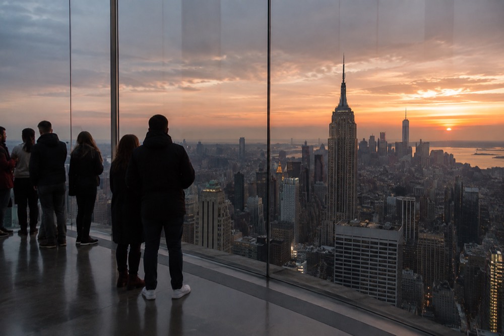A reflective glass observation room overlooking Manhattan at golden hour