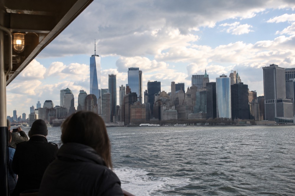 A wide view of Lower Manhattan and the harbor from a ferry deck