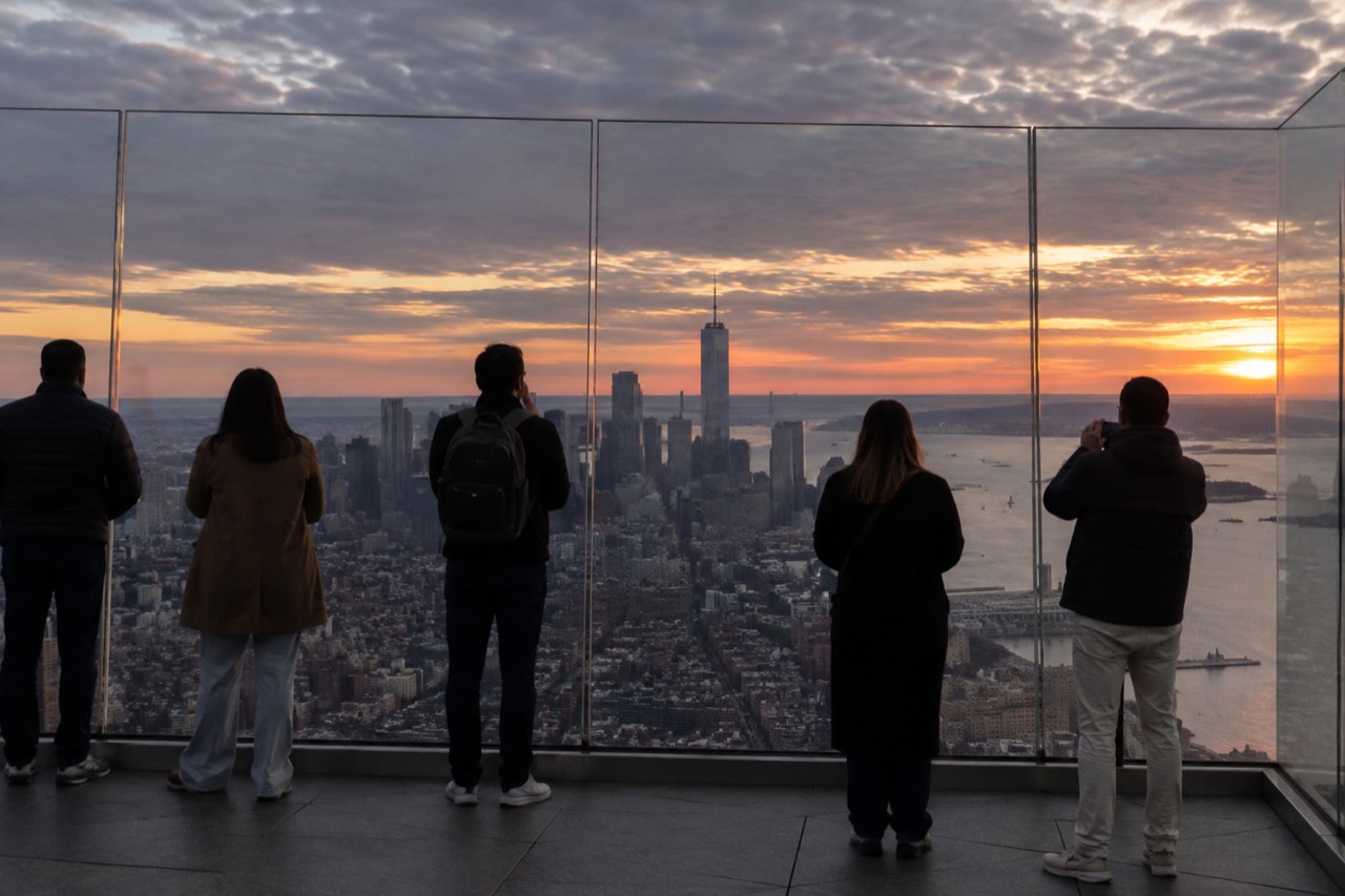 Visitors looking out over the Manhattan skyline from an observation deck at sunset