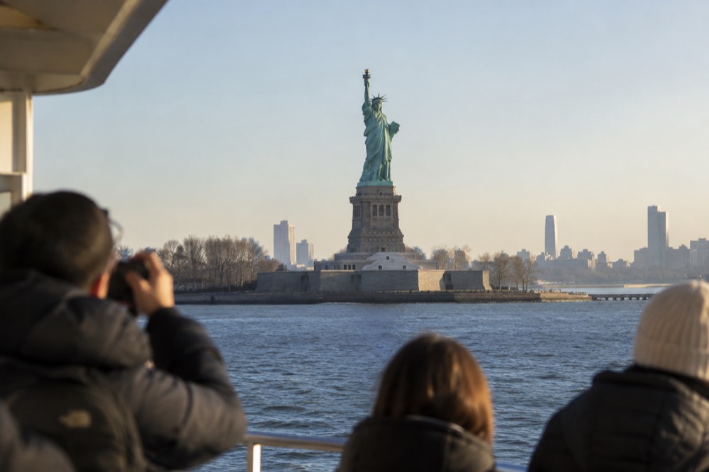 The Statue of Liberty seen from a ferry deck with the harbor behind it