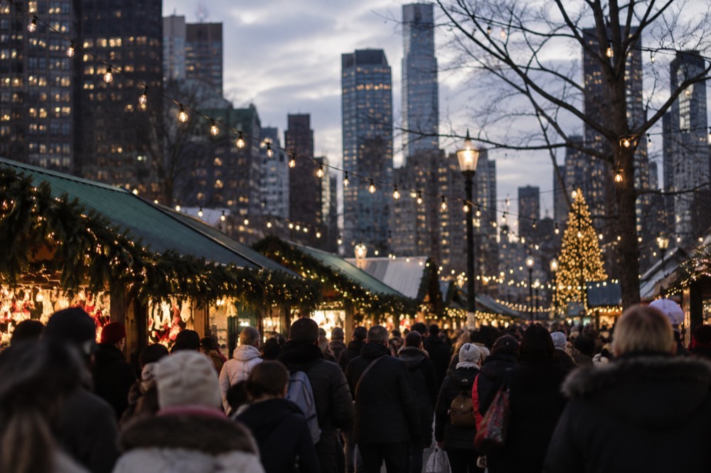 A Christmas market lit up at dusk with strings of white lights over the stalls