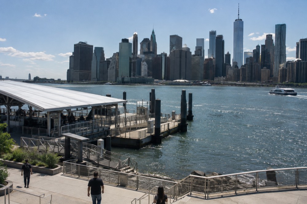 A ferry landing pier on the Brooklyn waterfront with the Manhattan skyline across the river