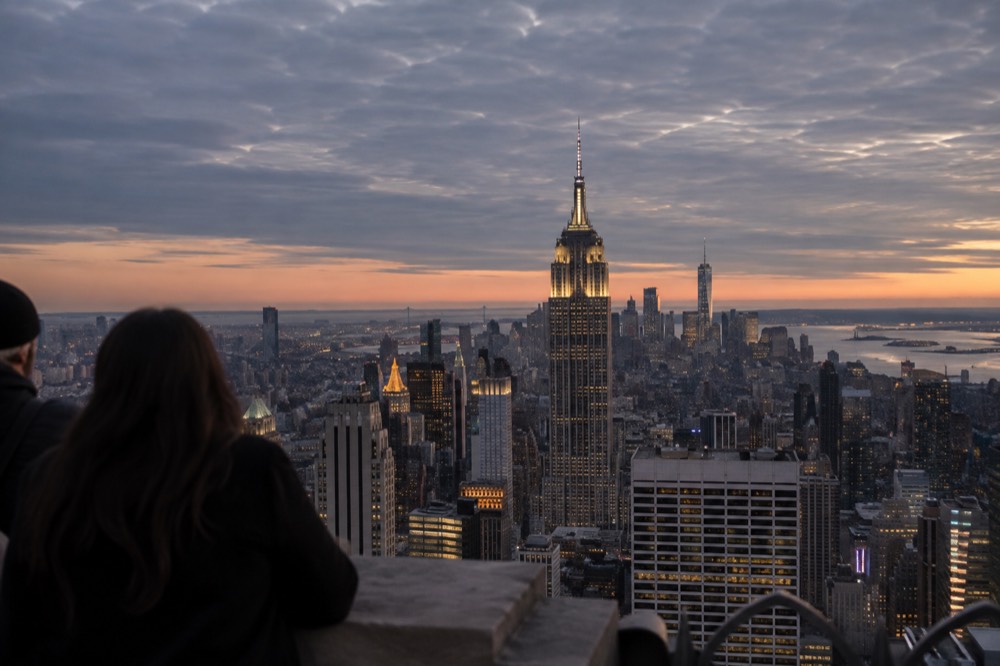 Manhattan skyline at dusk seen from a high observation deck with the Empire State Building lit in the distance