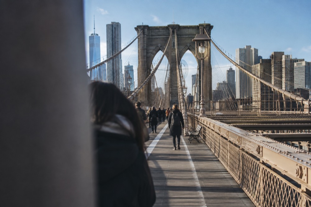 The Brooklyn Bridge walkway with its stone towers and cable pattern under a clear sky