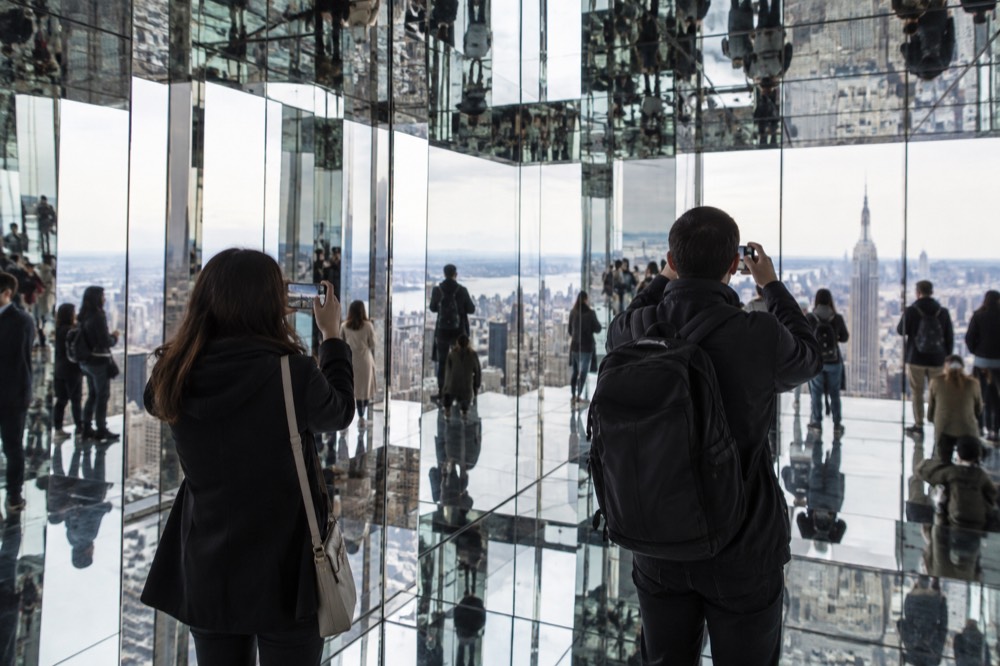 Visitors photographing the mirrored reflective room at a modern observation deck
