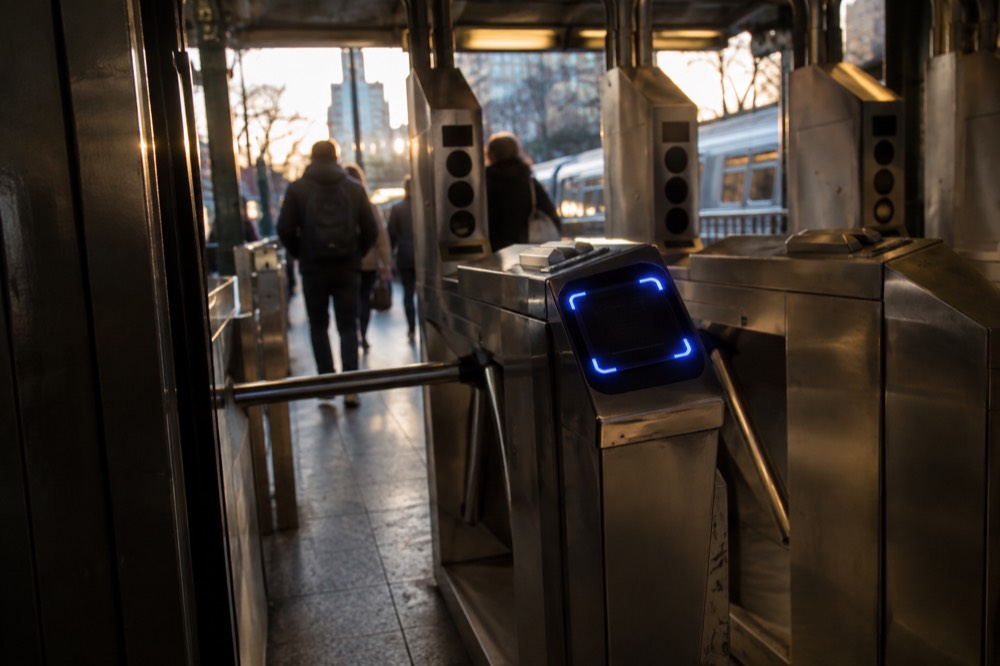 An OMNY reader glowing blue on a New York subway turnstile