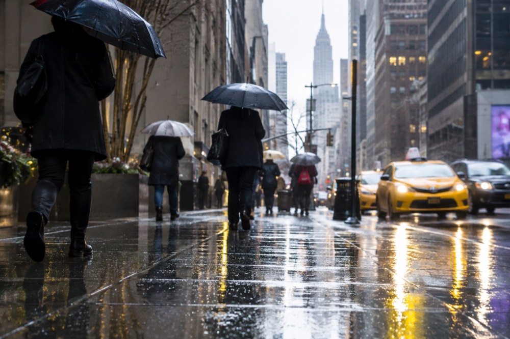 Umbrellas on a rainy New York street with yellow reflections on wet pavement