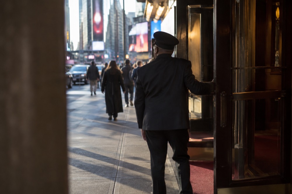 An usher opening the doors of a small theater lobby before a performance