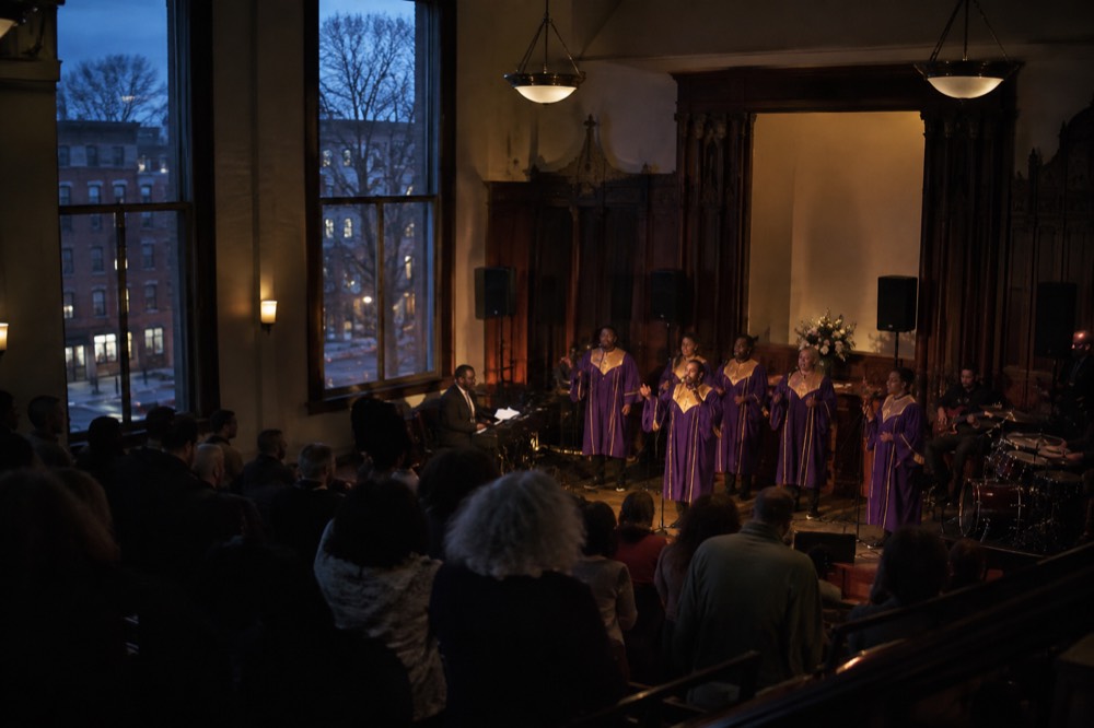 A gospel choir performing in a small Harlem venue with the audience close to the stage