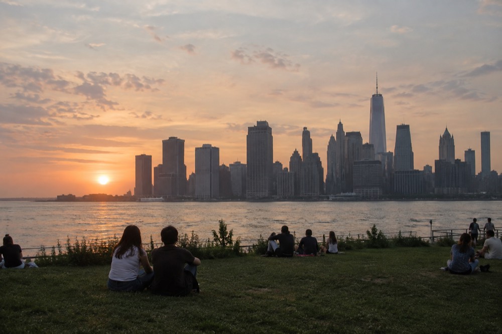 Waterfront park lawn with the Manhattan skyline across the river at sunset