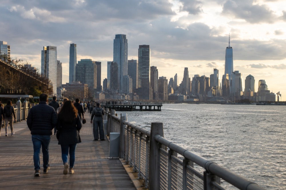 Wooden boardwalk along a waterfront with tall buildings visible in the distance