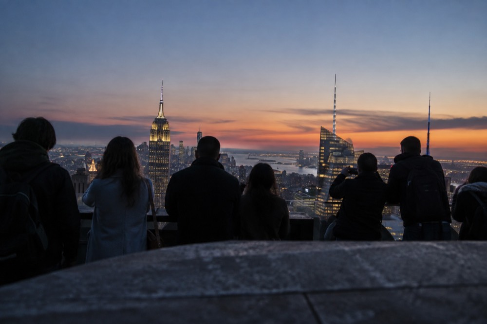 An observation deck in Manhattan with visitors looking out over the city at golden hour