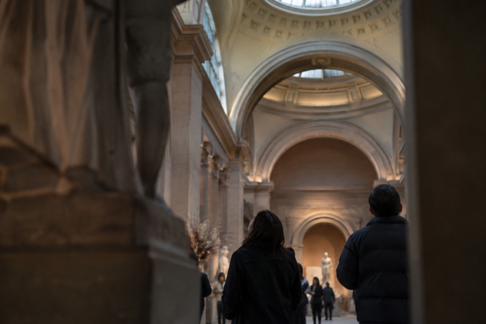 Visitors looking up at the ceiling of a grand museum gallery