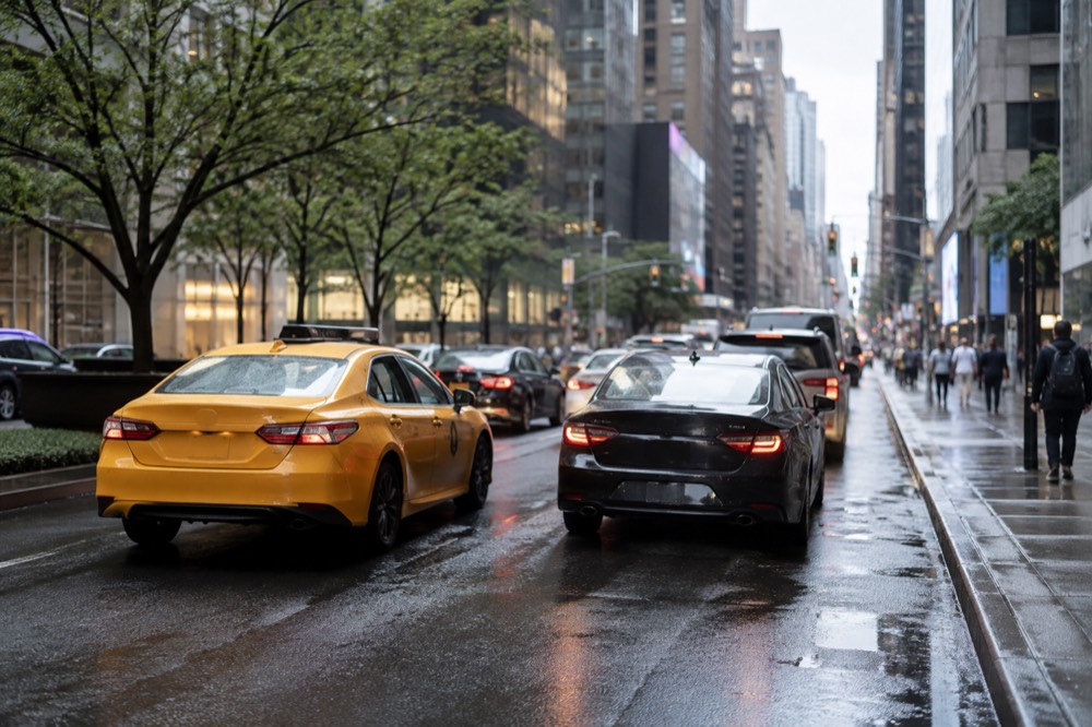 A yellow taxi and a rideshare car side by side in slow Manhattan traffic