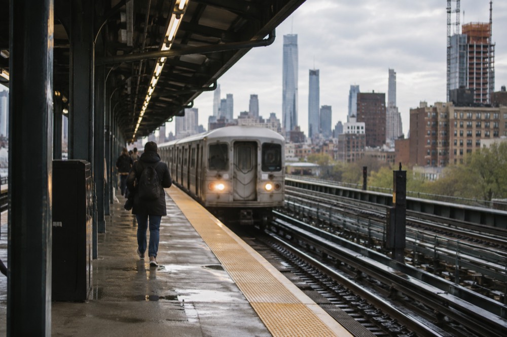 An elevated subway platform in Manhattan with a train arriving