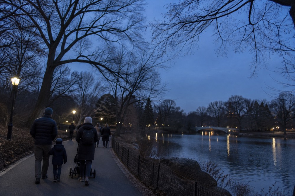 Families walking along a path beside a lake in Central Park