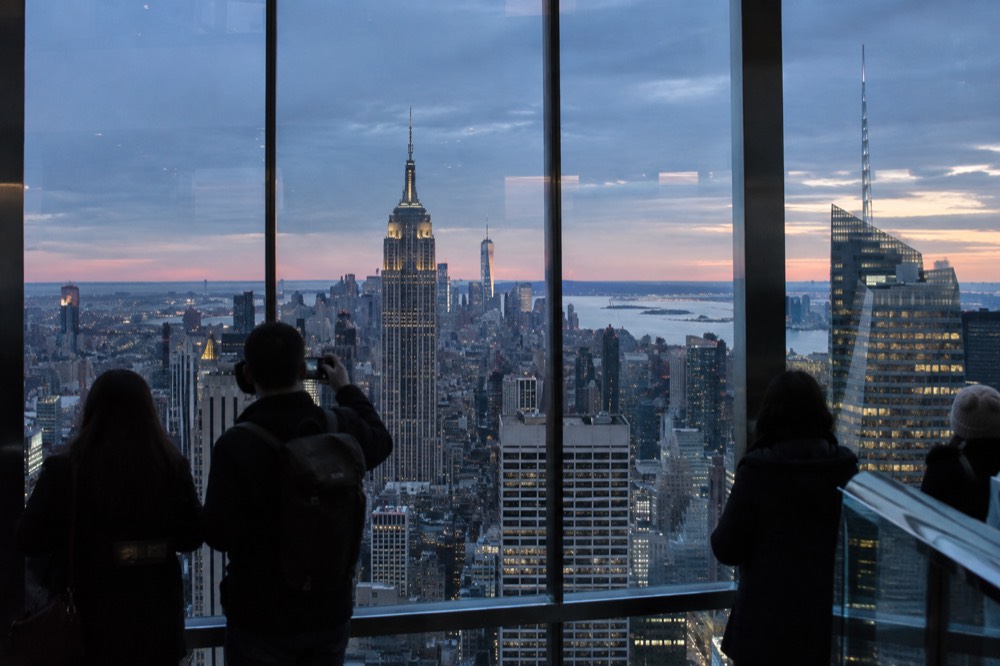 Looking down on Midtown Manhattan towers from a glass observation deck in morning light