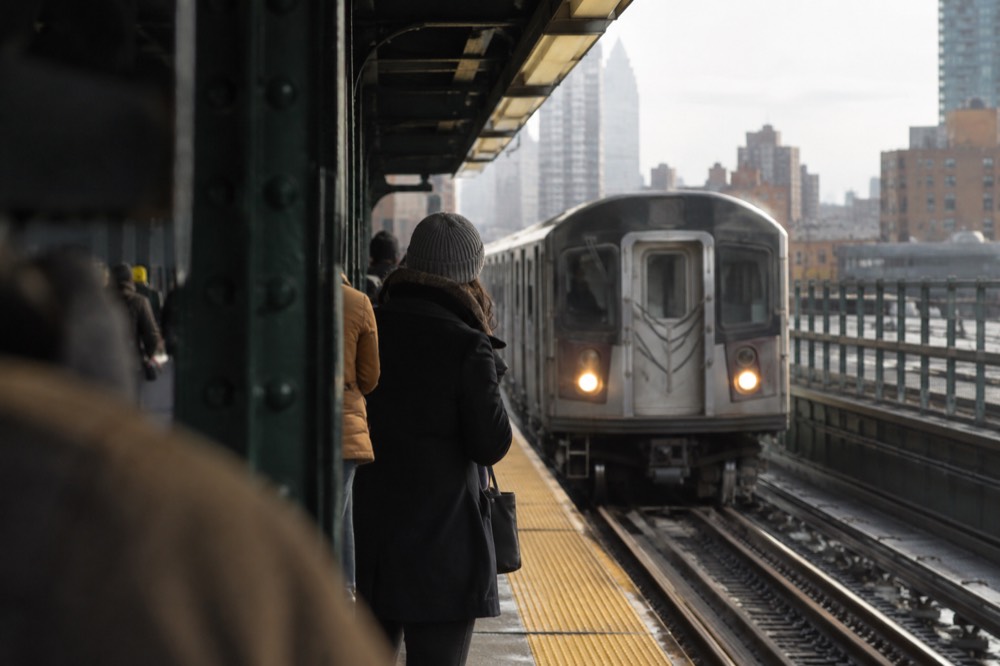 A subway platform with a train arriving and passengers waiting near the platform edge