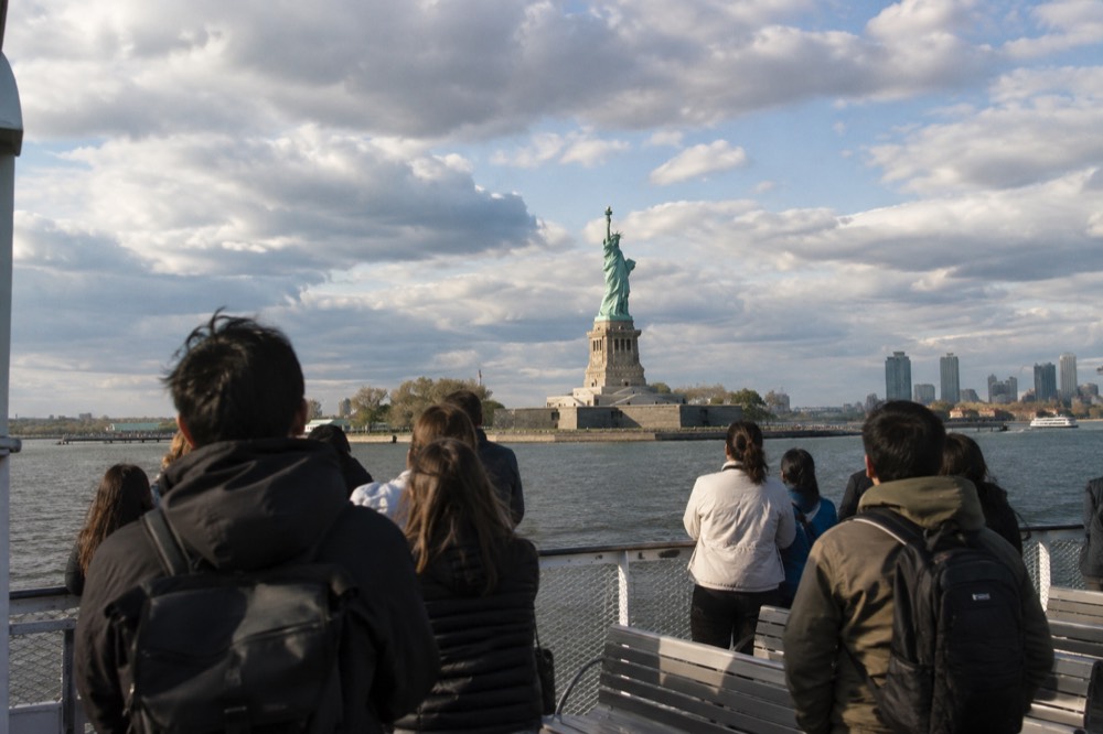 The Statue of Liberty seen from a ferry deck with visitors at the rail