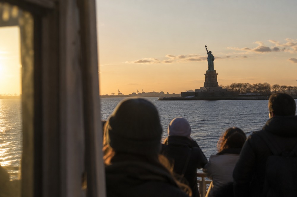 Ferry passengers on the deck of a boat approaching the Statue of Liberty in New York Harbor