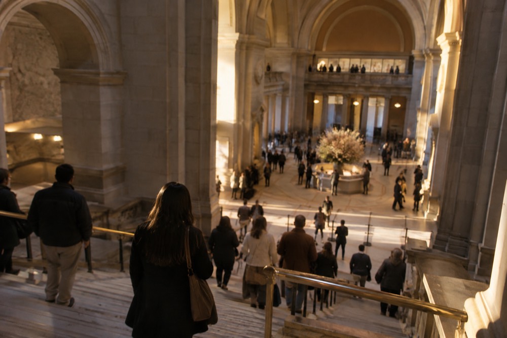 Visitors viewing grand staircases and stone architecture inside the Metropolitan Museum of Art