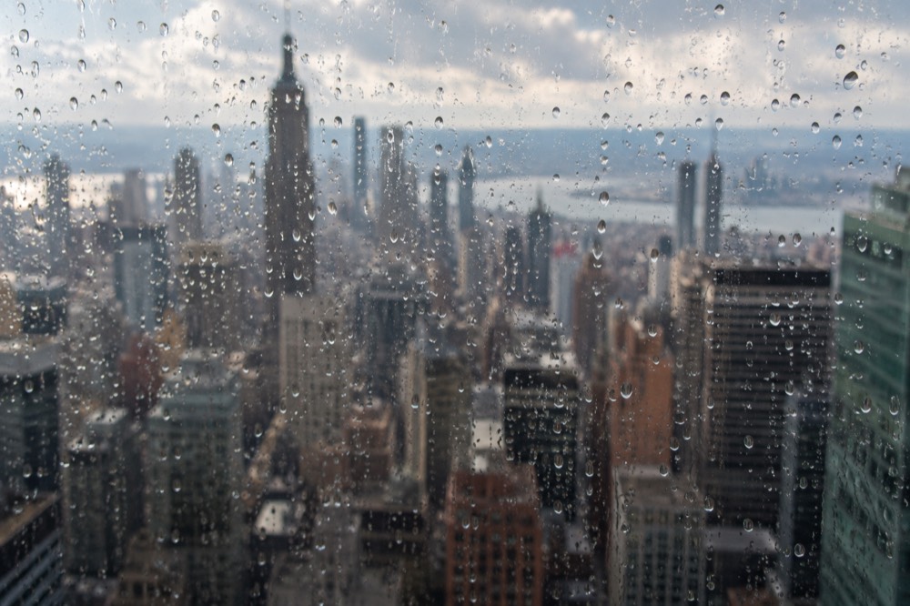 Raindrops on a window with the Manhattan skyline blurred behind the glass