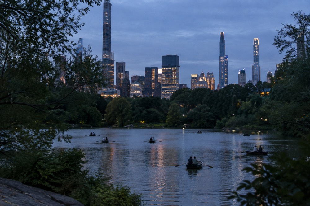 Rowboats on the lake in Central Park with the skyline behind the trees