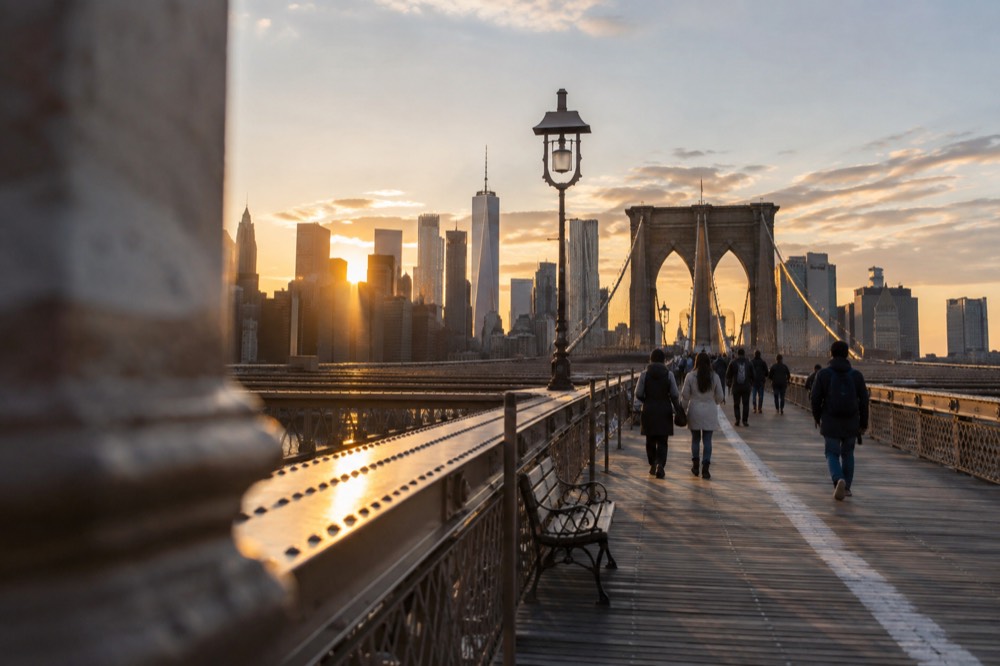 The Brooklyn Bridge promenade at sunset with the skyline behind it